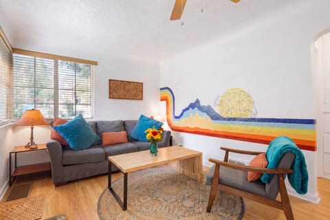 The living room, anchored by a hand-painted Colorado mural: mountains, the Denver skyline, and a geometric bear that nods to the Big Blue Bear.