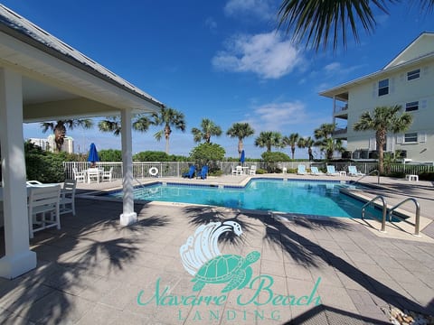 Shared pool area at Navarre Beach Landing. Includes restrooms, chairs, tables, and loungers.