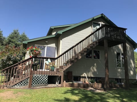 RIVER FACING SIDE OF COTTAGE WITH STEPS THAT LEAD UP TO THE BALCONY BEDROOM
