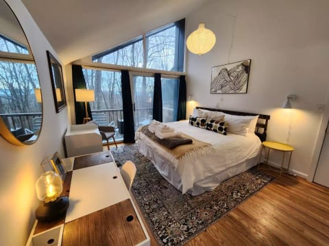 King bedroom with lovely views, 600-count cotton sheets, small deck with two white rockers, desk, dresser, and en suite bathroom.