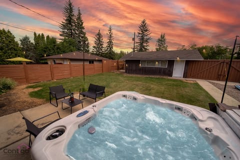 Relax in the private hot tub surrounded by a spacious backyard with yard games and cozy outdoor seating, perfect for family fun in the heart of the neighborhood.
