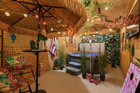 Escape to your own tropical oasis! Relax and unwind in the shared hot tub surrounded by lush greenery and tiki vibes.