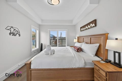 Bright and cozy second queen bedroom with alpine-inspired décor, premium white bedding, and serene mountain views — comfortably sleeping extra guests at this top-rated Golden, BC condo.