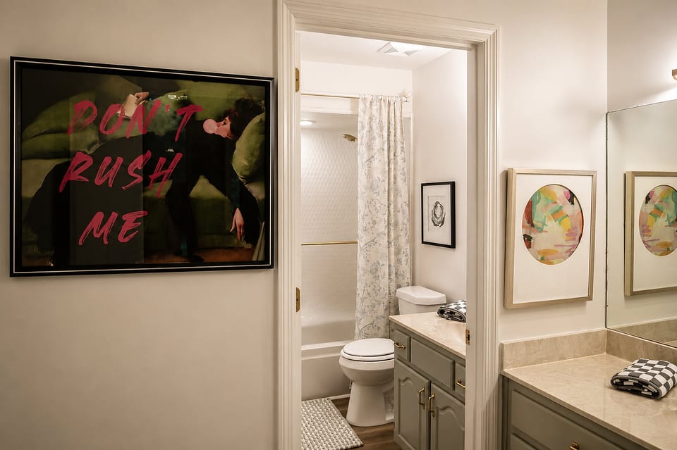 Stylish dual bathroom setup with elegant vanity and bold art accents