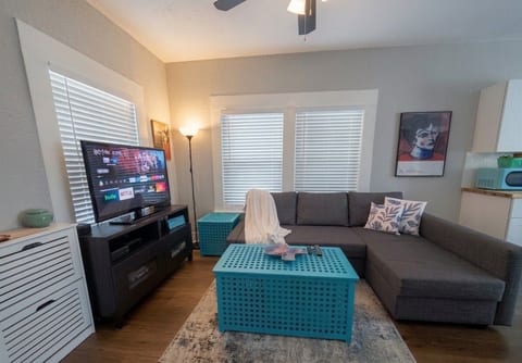 Relax in this sunlit living room featuring a cozy sectional sofa bed and flat-screen TV with streaming apps. Large windows provide plenty of natural light, making it a great spot to unwind after exploring San Antonio!