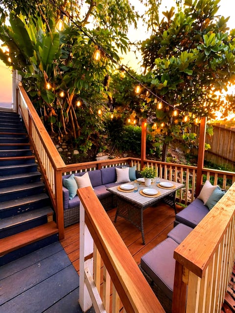 Cozy deck oasis with string lights, cushioned seating, and garden views