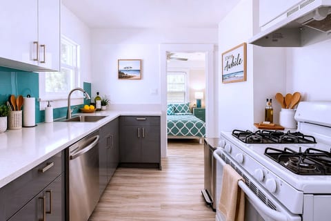 Bright galley kitchen with gas range, quartz counters, and dishwasher.