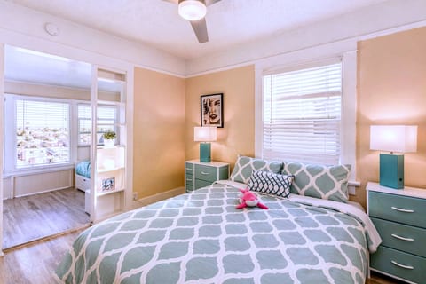 Sunny bedroom with queen bed, ceiling fan, and bright sunroom views.