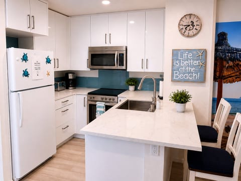 Bright coastal kitchen with bar seating and modern stainless appliances
