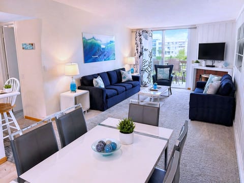 Sunny coastal lounge with balcony, plush sofas, and open dining flow