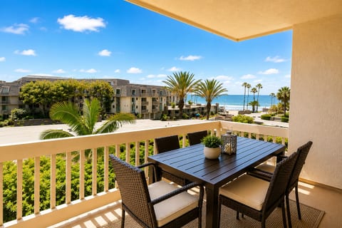 Private ocean-view balcony with outdoor dining and palm-lined scenery