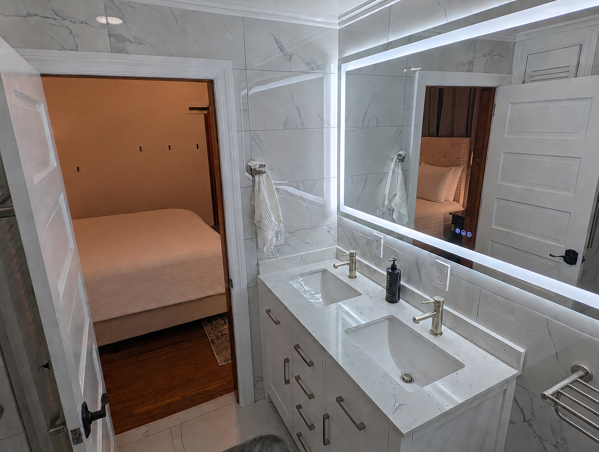 Premier suite dual sink vanity, frontlit mirror, looking towards King bed.