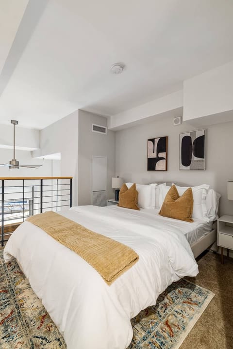 Bright loft bedroom with plush king bed, modern decor, and airy open layout