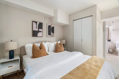 Bright modern bedroom with en suite bath, cozy linens, and sleek closet storage