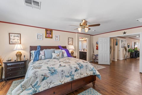 Spacious primary bedroom with king bed, wood floors, and ensuite access
