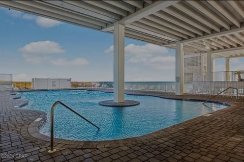 Covered poolside seating area with shade and coastal breezes.