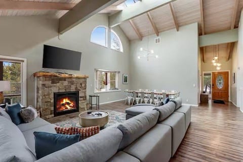 Vaulted great room with stone fireplace, large sectional, and dining space