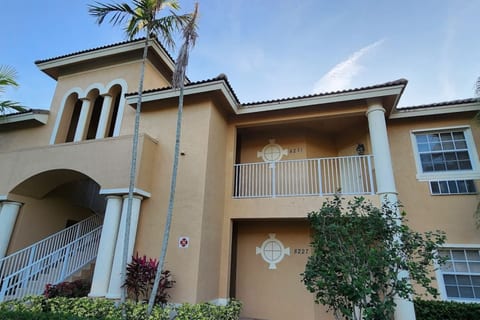 Exterior view of the building with covered entryways, tropical landscaping, and Florida-style architecture.