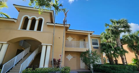 Exterior view of the building with covered entryways, tropical landscaping, and bright Florida-style architecture.