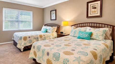 Comfortable bedroom featuring two beds, coastal-inspired bedding, ceiling fan, and plenty of natural light.