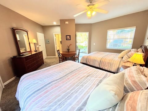 Bright bedroom featuring two beds, dresser storage, mirror, and a relaxed, welcoming layout.