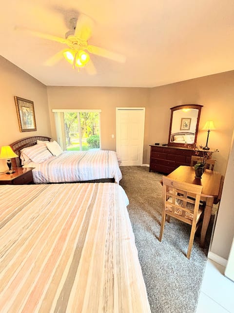 Bright bedroom featuring two beds, dresser storage, mirror, and a relaxed, welcoming layout.