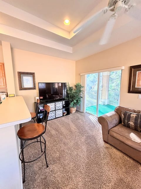 Cozy living area with breakfast bar seating, large TV, comfortable sofa, and sliding glass doors leading out to the private balcony.