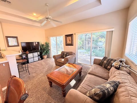 Comfortable living area with cozy seating, high ceilings, large TV, and sliding glass doors that open to the private balcony.