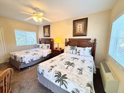 Bright bedroom featuring two beds, ceiling fan, bedside lighting, and a clean, relaxing layout.