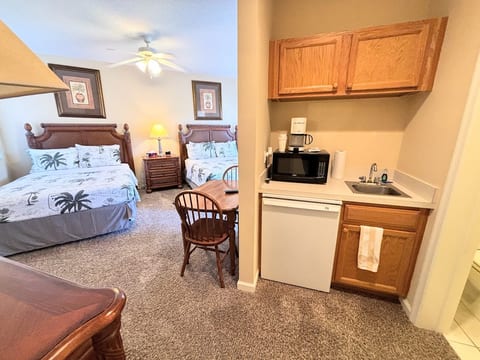 Comfortable bedroom with two beds, in-room kitchenette, small table, and convenient bathroom access.