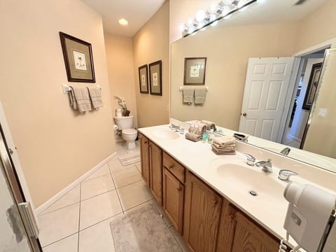 Spacious bathroom with double-sink vanity, large mirror, tile flooring, and plenty of counter space.