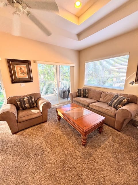 Cozy living room with sofa and chair seating, large windows, and easy access to the screened balcony.