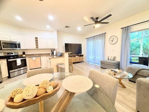 Bright modern open-concept living and dining area featuring updated finishes, comfortable seating, a fully equipped kitchen, and sliding glass doors leading to the outdoor space.