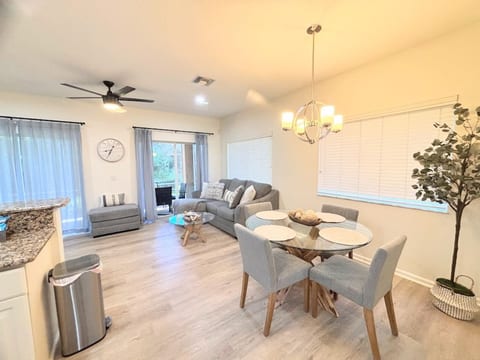 Bright and stylish dining and living area with modern furnishings, wood-look flooring, comfortable seating, and sliding glass doors leading to the outdoor space.