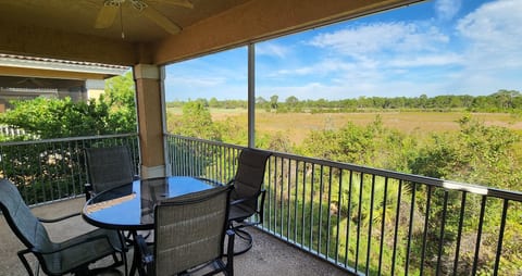 Private screened balcony with outdoor seating and relaxing views of the surrounding green space.