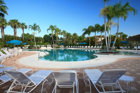 Beautiful community pool area with lounge seating, palm trees, and a relaxing resort-style feel.