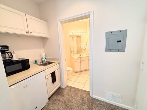 Convenient kitchenette area with microwave, mini fridge, sink, and easy access to the bathroom.