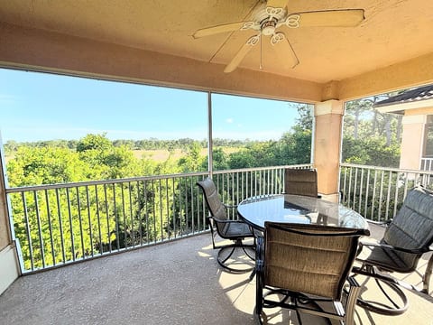 Private screened balcony with outdoor seating and beautiful views of the surrounding green space.
