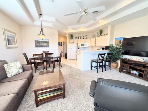 Open-concept living, dining, and kitchen area with comfortable furnishings, breakfast bar seating, and a bright, welcoming layout.