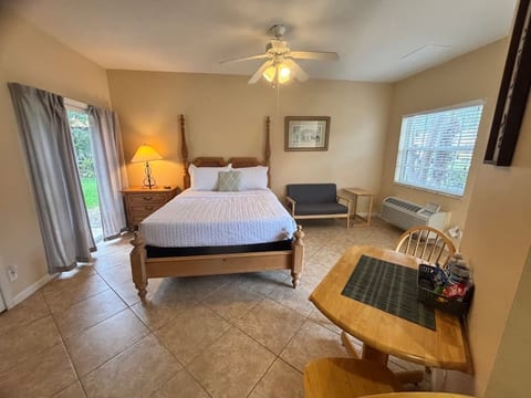 Bright bedroom featuring a large bed, cozy seating, bedside lighting, and convenient in-room table space.