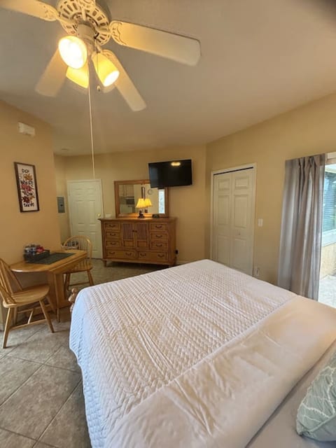Spacious bedroom with dresser storage, TV, small table with seating, and a clean, relaxing setup.
