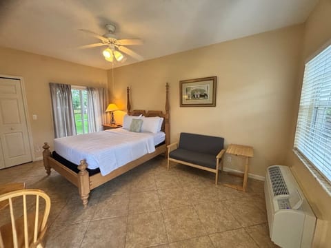 Comfortable bedroom with a large bed, ceiling fan, sitting bench, and peaceful window views.