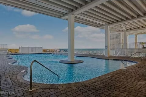 Covered poolside seating area with shade and coastal breezes.