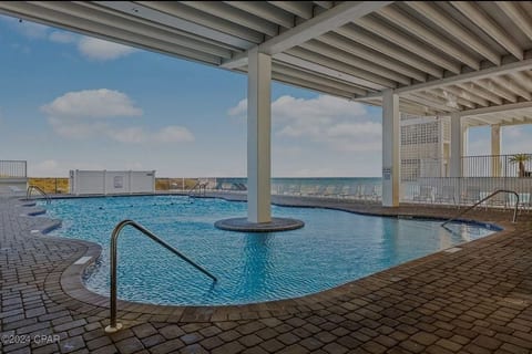 Covered poolside seating area with shade and coastal breezes.