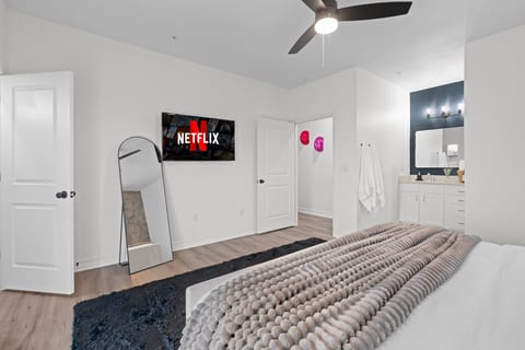 Bright modern bedroom with en suite bath, TV, and stylish cozy touches