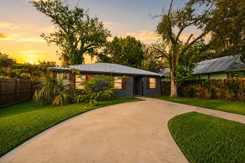 Charming home with curved driveway, lush yard, and glowing sunset curb appeal