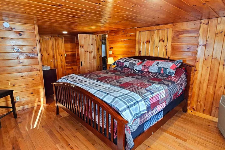Cozy king bedroom with warm wood interiors and rustic cabin charm.