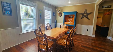 Rustic dining room with handcrafted wood table, seating for eight, hardwood floors, and charming Maine lodge décor.