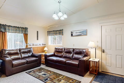 Cozy living room with comfortable seating, warm lighting, and a relaxing cabin atmosphere.
