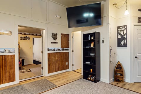 Living area with large TV, shelving, and easy access to bedrooms and common spaces.